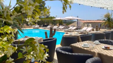 Piscine extérieure avec chaises longues et tables dressées.