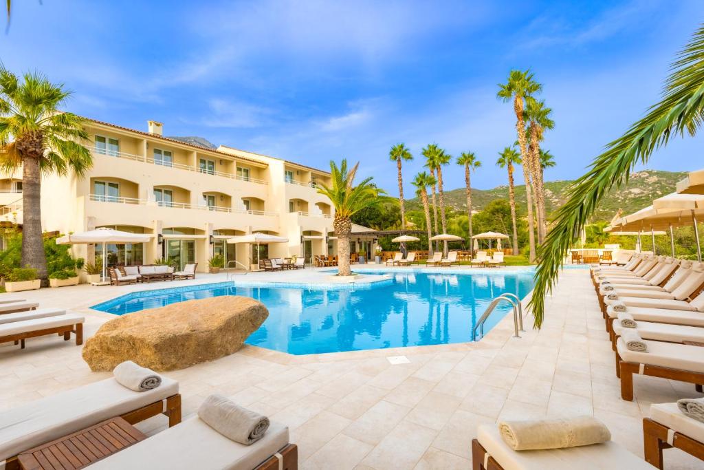 Piscine d'hôtel entourée de palmiers et transats.