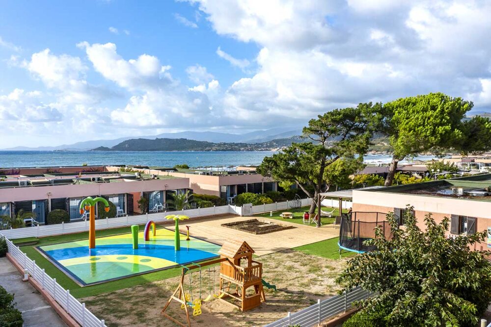 Vue sur jardin avec aire de jeux et mer.