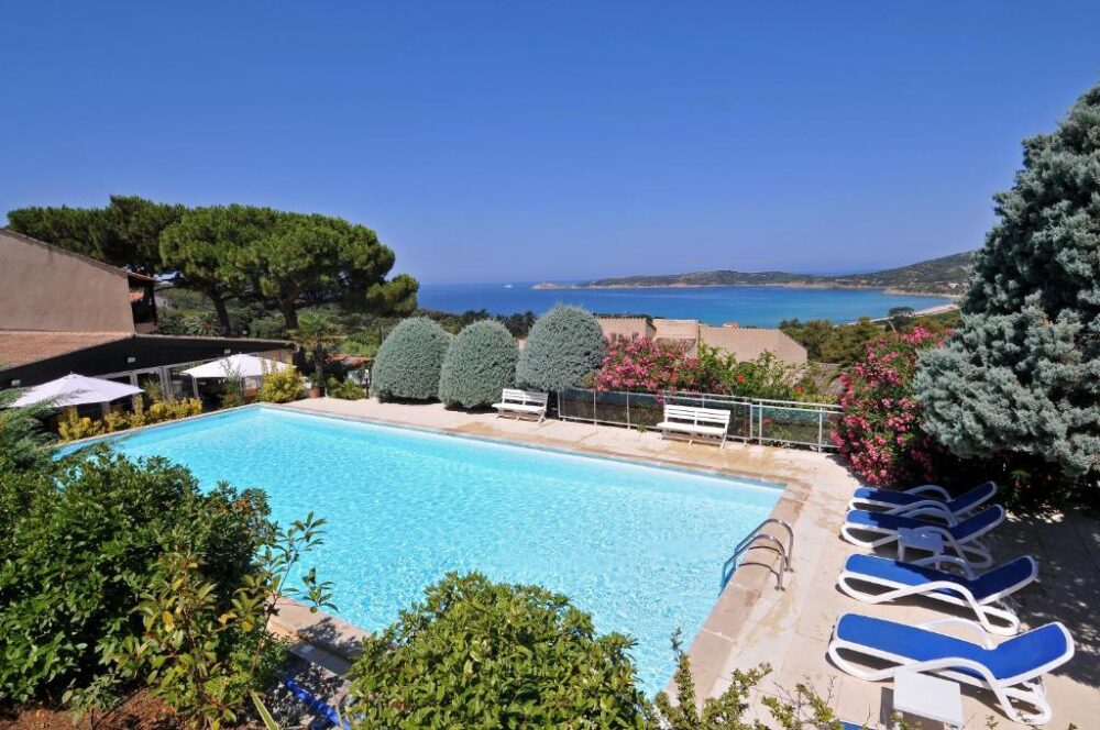 Piscine avec vue sur la mer et collines verdoyantes.