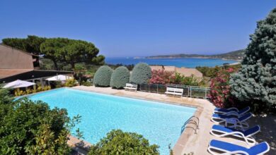 Piscine avec vue sur la mer et collines verdoyantes.