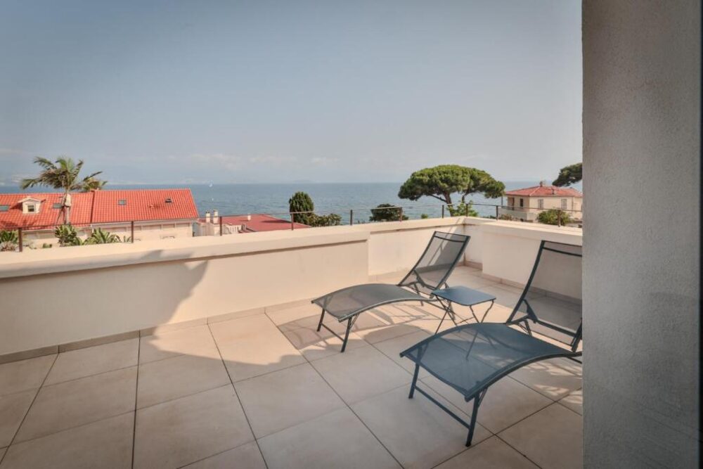 Terrasse avec vue sur mer et chaises longues.