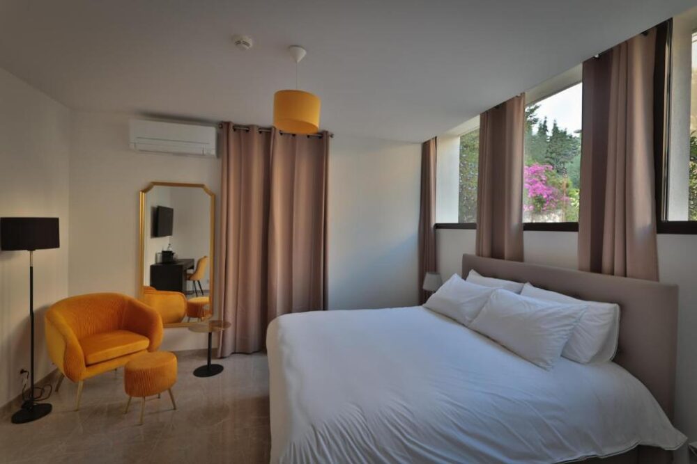 Chambre moderne avec lit double et fauteuil jaune.