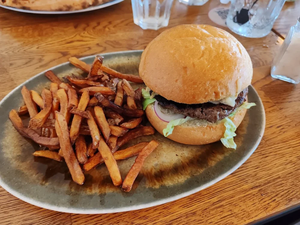 Hamburger avec frites sur assiette en bois.