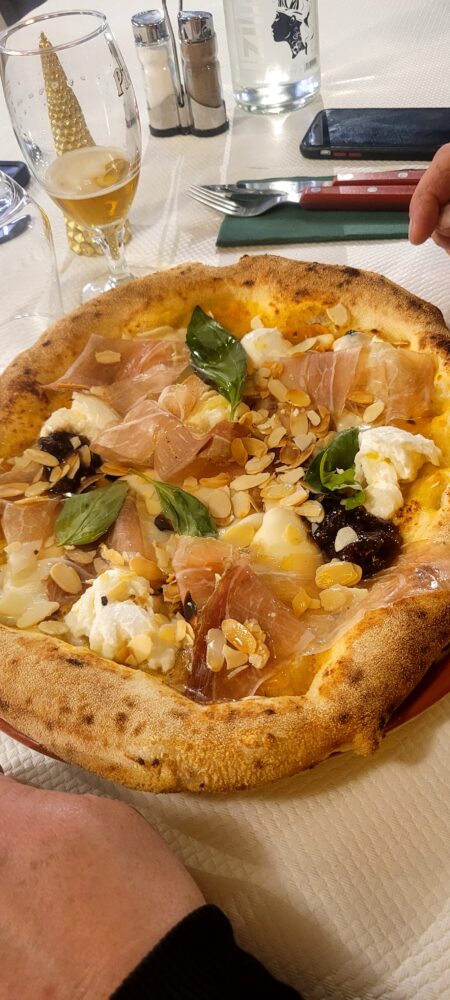 Pizza avec prosciutto, basilic et amandes effilées.