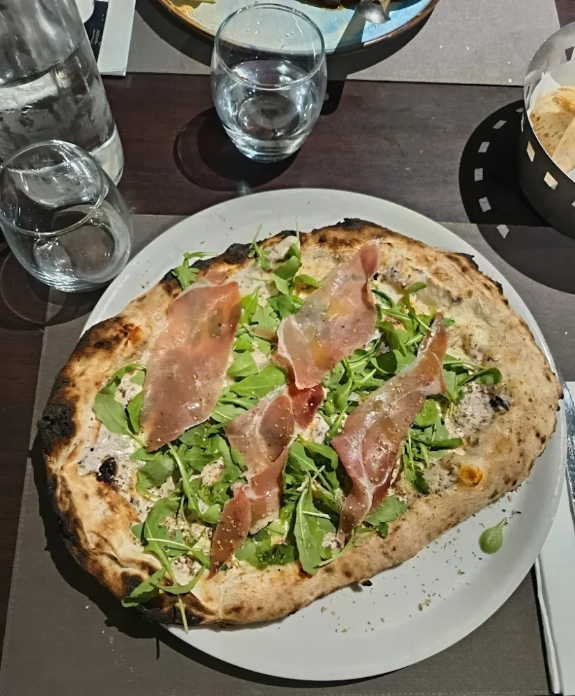 Pizza roquette et jambon cru sur assiette.